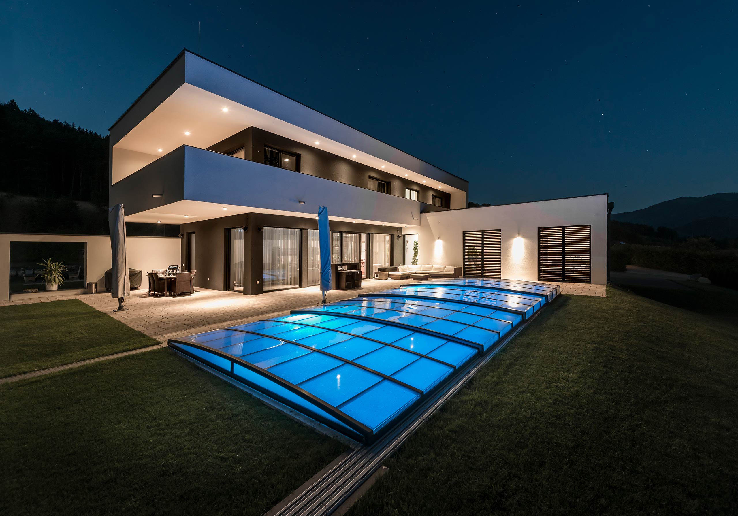 Poolüberdachung Ultraflat in der Nacht mit beleuchtetem Pool